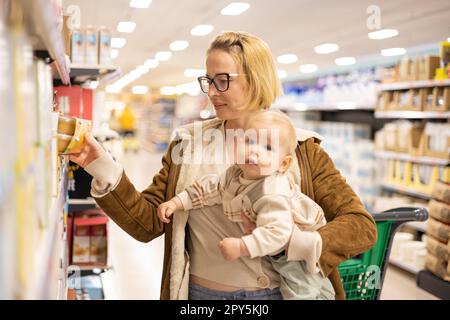 Kaukasische Mutter kauft mit ihrem kleinen Jungen Produkte aus dem Supermarkt ein. Stockfoto