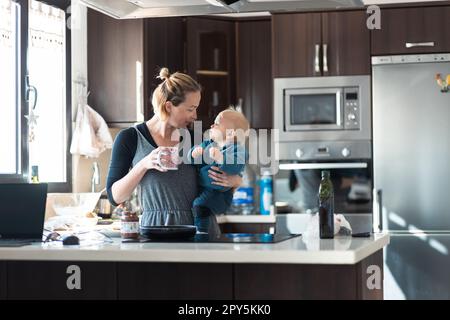 Glückliche Mutter und kleiner kleiner Junge, die zusammen Pfannkuchen zum Frühstück in der Hausküche machen. Familie, Lebensstil, häusliches Leben, Essen, gesunde Ernährung und Menschen Konzept. Stockfoto