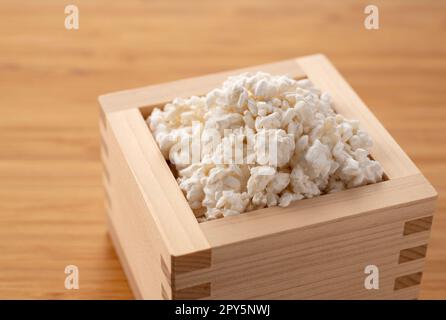 Reis-Koji in einer Masu-Box vor einem Holzhintergrund. Koji-Schimmel. Stockfoto