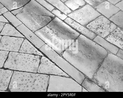Marmorboden auf der Straße, Dubrovnik, Kroatien. Antike Mauerwerksteine rechteckige Blöcke. Metamorphes Gestein, bestehend aus Calcit CaCO3. Abfluss, Holzkohle für Wasser. Schwarzweiß-Monochrom Stockfoto