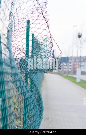 Der grüne beschädigte Drahtgitterzaun wird nach einem Unfall als zertrümmerter Zaun für die Kfz- und Sachversicherung zerstört und verliert durch Vandalismus und Abriss von Barrieren Sicherheit und Sicherheit Stockfoto