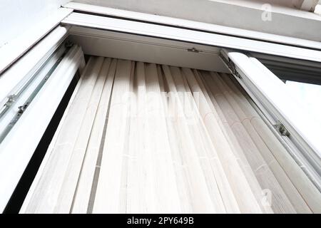 Weiße, grobe Baumwolle- oder Leinenvorhänge aus Gewebungen aus dünnen Fäden. Einfache, kompakte und kostengünstige Wohnungseinrichtung. Fensterdekoration im Zimmer. Roter Streifen. Stockfoto