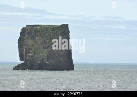 Malerischer Blick auf die isländische Halbinsel mit Wellen auf riesigen schwarzen Felsen am bedeckten Dyrholaey Cape Stockfoto