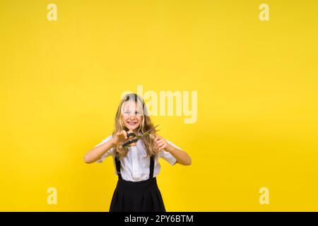 Teenager-Schulmädchen mit Schere, isoliert auf gelbem Hintergrund. Kinderkreativität, Kunst und Handwerk. Stockfoto