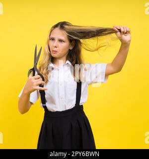 Teenager-Schulmädchen mit Schere, isoliert auf gelbem Hintergrund. Kinderkreativität, Kunst und Handwerk. Stockfoto