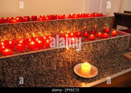 Memorial Day mit Kerze. Gedenkkerzen sind angezündet. Auf dem Friedhof brennen Kerzenflammen. Brennende Kerzen in der katholischen Kirche in Dubrovnik, Kroatien. Viele Kerzen. Die Flamme schwankt im Zug Stockfoto