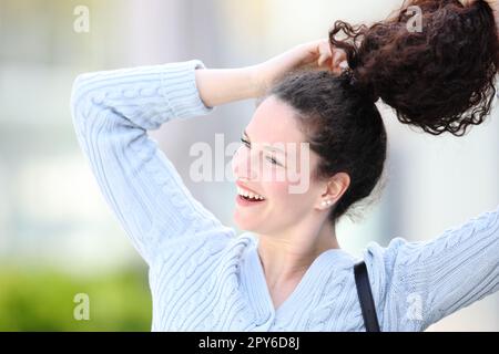 Glückliche Frau, die Pferdeschwanz im Freien macht Stockfoto