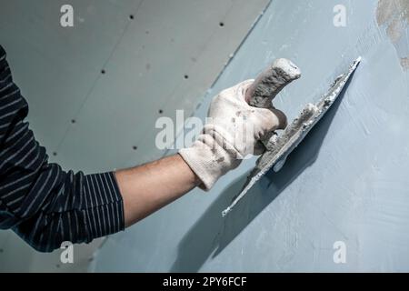 Handarbeit mit einer Kelle zum Abdichten der Wand Stockfoto