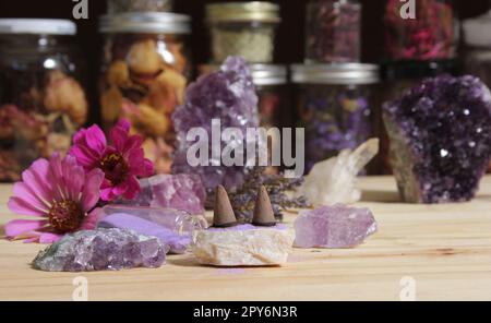 Amethyst-Kristalle mit Blumen und Räucherkegel auf Meditationstisch Stockfoto