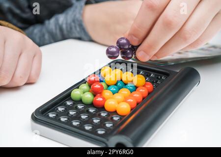 Kinder spielen Spielzeugbauer auf Tischnaht. Die Hände von Kindern sammeln farbige Details auf dem Spielbrett. Stockfoto