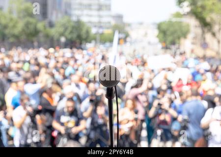 Fokus auf Mikrofon, verschwommene Gruppe von Menschen bei Massenprotesten im Hintergrund Stockfoto