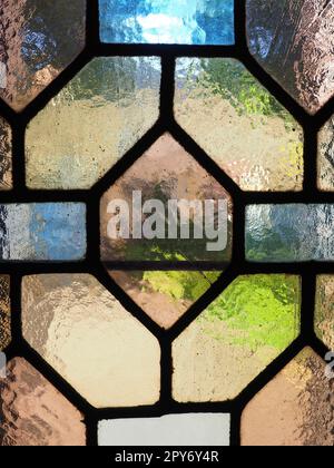 Fenster mit altem Buntglas. Mehrfarbige Stücke aus transparentem Glas. Ein wunderschönes Fenster, durch das Licht in den Raum eindringt. Dekoration einer alten christlichen Kirche oder eines Tempels. Stockfoto