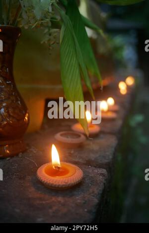 Nahaufnahme beleuchteter Teelichterkerzen vor dem buddhistischen Tempel in Thailand Stockfoto