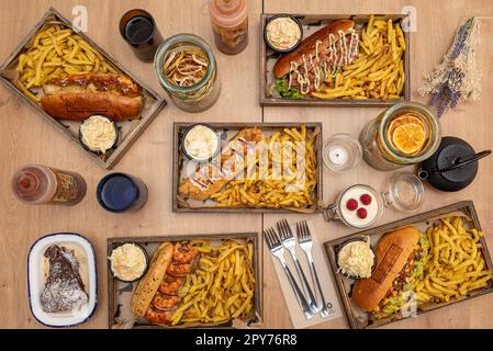 Eine Auswahl an Gourmet-Hot-Dog-Gerichten, alle begleitet von einer großzügigen Portion Kartoffeln Stockfoto