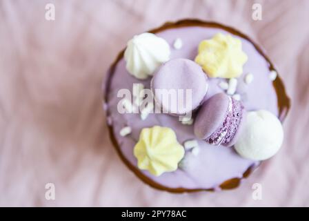 Ein traditioneller paska mit weißer Schweizer Schokolade und Baiser steht auf einer lavendelfarbenen Tischdecke. Osterurlaub, Draufsicht. Platz für die Beschriftung. Stockfoto