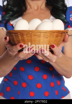 Frau in Retro-Kleid, die einen Korb mit frischen Eiern hält Stockfoto