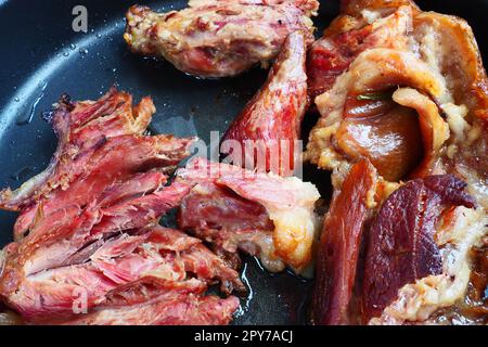 Schulter oder Knie von geröstetem, geräuchertem Schweinefleisch. Köstliches Fleisch auf einem schwarzen Backblech mit Tropfen Pflanzenöl, das aus dem Ofen genommen wurde. Schweinefleisch zum Abendessen in einem Restaurant und Familienessen. Rotes Fleisch Stockfoto
