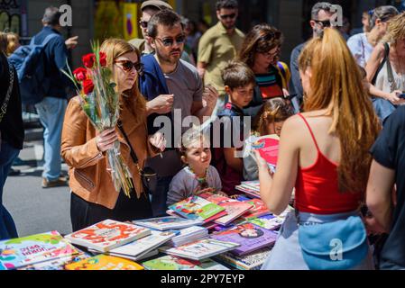 Barcelona, Spanien - 23. April 2023: Während der traditionellen katalanischen Feste von Sant Jordi werden Menschen gesehen, die Bücher kaufen und dabei rote Rosen halten Stockfoto