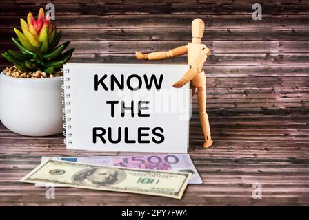 Machen Sie sich mit den Regeln vertraut, und machen Sie sich mit inspirierenden Zitaten aus geschäftlichen Gründen auf einem Holztisch mit Dollar- und Euro-Banknoten vertraut Stockfoto