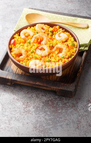 Aromatischer spanischer gelber Reis und Garnelen mit Gemüse und Gewürzen auf dem Teller auf dem Tisch. Vertikal Stockfoto