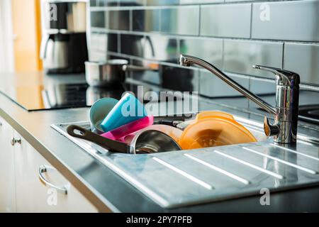 Das Waschbecken war voller schmutzigem Geschirr. Dunkle Arbeitsfläche in moderner Küche. Hausarbeit-Konzept Stockfoto
