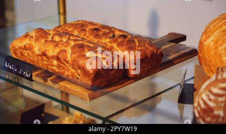 Nahaufnahme eines frisch gebackenen Brotlaibs, ausgestellt unter anderem mit verschiedenen Gebäcksorten Stockfoto