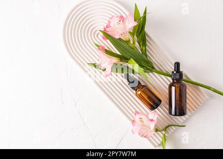 Verjüngungsserum für das Gesicht, ein organisches Naturmittel in zwei Glasflaschen auf einem weißen Podium in Form eines Bogens. Draufsicht. Ein Kopierbereich Stockfoto