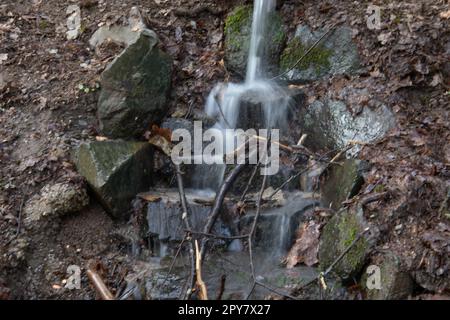 Flusslauf übersät mit Felsen mit Wasserfall im Siegerland Stockfoto