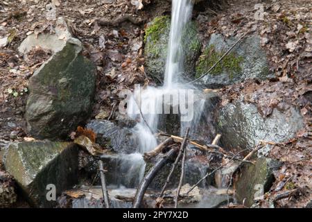 Flusslauf übersät mit Felsen mit Wasserfall im Siegerland Stockfoto