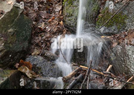 Flusslauf übersät mit Felsen mit Wasserfall im Siegerland Stockfoto