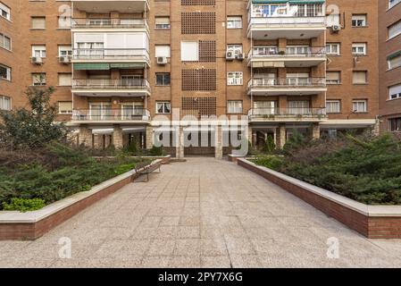 Hauptfassade eines Wohngebäudes mit großen Blumenkästen und Holzbänken zur Entspannung der Bewohner Stockfoto