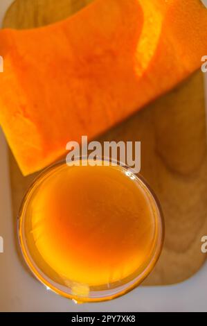 Den Kürbis Smoothie in ein Glas und rohe Kürbis auf hölzernen Hintergrund ausschneiden, Ansicht von oben Stockfoto