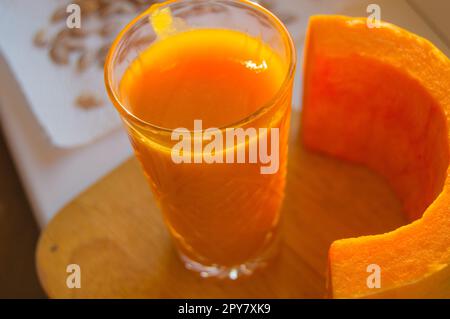 Den Kürbis Smoothie in ein Glas und rohe Kürbis auf hölzernen Hintergrund ausschneiden Stockfoto