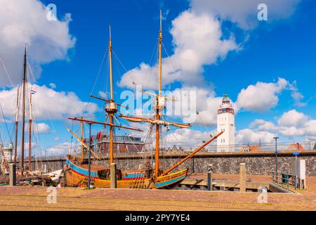 Altes Schiff und Leuchtturm im Hafen von Harlingen, Provinz Friesland, Niederlande, am sonnigen Frühlingstag Stockfoto