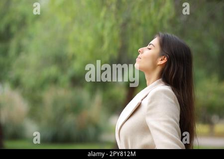 Eine Frau, die im Winter in einem Park atmet Stockfoto