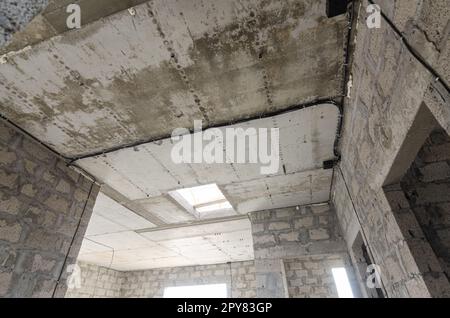 Bau eines einzelnen Wohngebäudes, Blick auf die monolithisch verstärkte Betondecke im Haus mit einer Öffnung für die Treppe in die zweite Etage Stockfoto