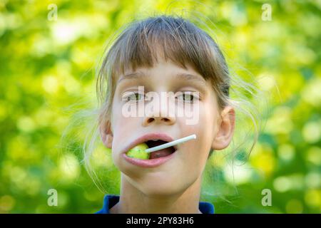 Das Mädchen hat einen großen runden Lutscher im Mund, Nahaufnahme Porträt Stockfoto