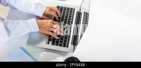 Die Hände der Ärztin tragen Uniform im Krankenhaus sie tippt Informationen auf Tastatur Laptop Stockfoto