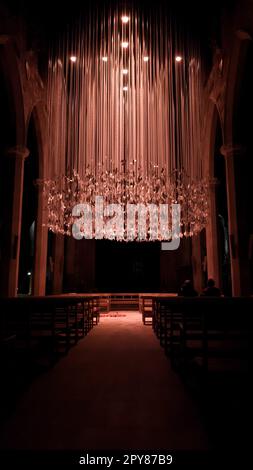 Das Innere einer christlichen Kirchenkathedrale ist mit Sitzen und Bänken zum Sitzen und Beten ausgestattet und mit LED-Kronleuchtern im ceili dekoriert Stockfoto