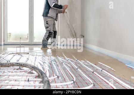 Aufbringung von Beton auf dem Boden bei Fußbodenheizungen Stockfoto