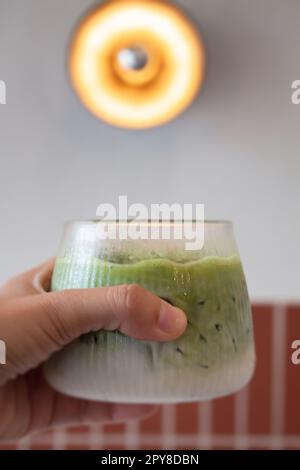Handgehaltener Eistee mit Matcha-Grün Stockfoto