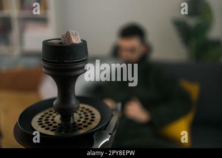 Hookah Shisha mit Glaskolben und Metallschüssel im Raum mit Männerhintergrund und Kopierbereich und leerem Platz für Text. Traditioneller Osturlaub zur Entspannung Stockfoto