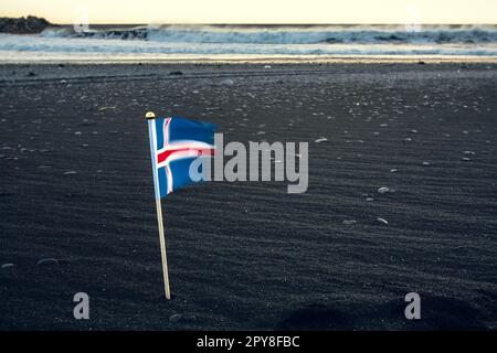 Nahaufnahme der isländischen Flagge auf schwarzem Sandstrand Konzeptfoto Stockfoto