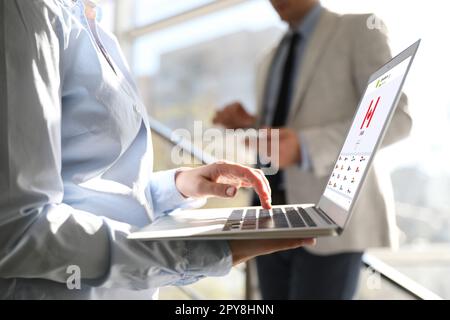 Frau, die ein modernes Notebook mit eingeschaltetem VPN im Büro verwendet, Nahaufnahme Stockfoto