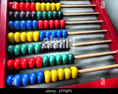 Bildungskonzept - Abakus mit vielen bunten Perlen. Rote, blaue, grüne, schwarze, gelbe Details auf dem Abakus. Mathematische Übungen. Schulprogramm Stockfoto