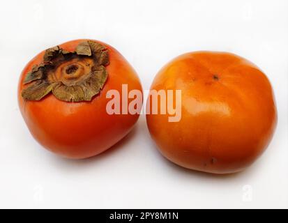 Persimone ist die essbare Frucht einer Reihe von Baumarten der Gattung Diospyros. Die Persimonen werden frisch, getrocknet, roh oder gekocht gegessen. Stockfoto