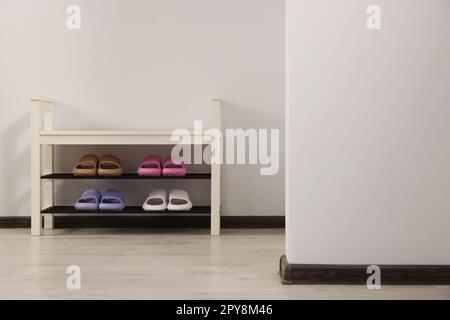 Aufbewahrungsbank mit Paar Gummipantoffeln im Innenbereich Stockfoto