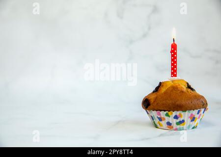 Geburtstagskuchen mit einer roten Geburtstagskuchen-Kerze auf weißem Hintergrund mit Kopierraum an der Seite, alles gute zum Geburtstag, Partykonzept Stockfoto