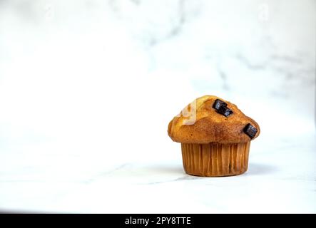 Ein Stapel köstlicher Chocolatechip Banana Muffins und Blaubeeren auf weißem Hintergrund, leckere gesunde Snack Müsli Frühstück Muffin Stockfoto