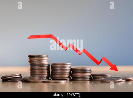 Inflation. Die Rezession der Wirtschaft und des Euro. Das Konzept des wirtschaftlichen Zusammenbruchs und des Zusammenbruchs der Börse in der Eurozone. Stapel von Münzen und ein nach unten zeigender Pfeil. Stockfoto